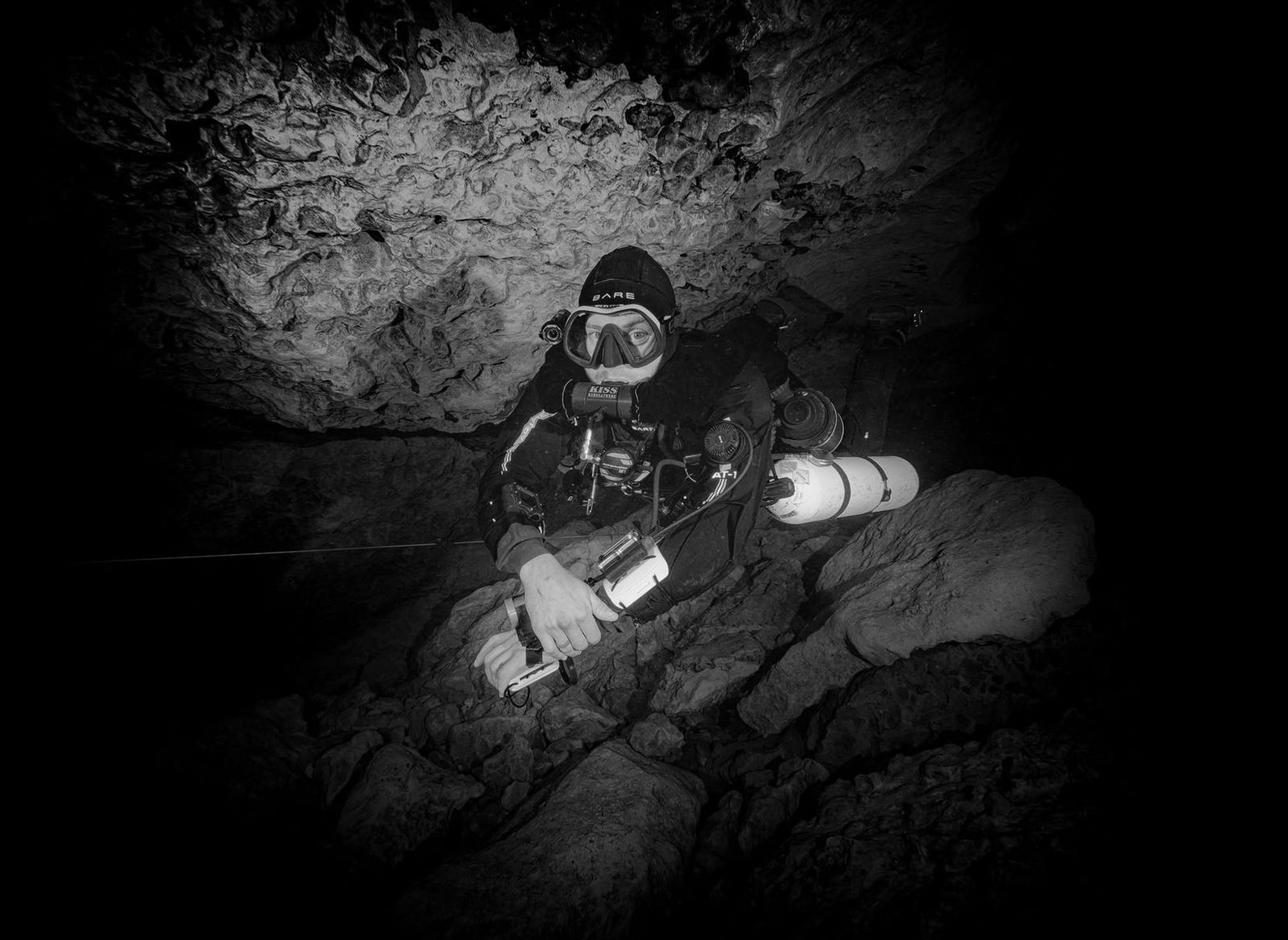 Mehdi Zinetti on a KISS Sidewinder sidemount rebreather resting on the cave floor beside the line